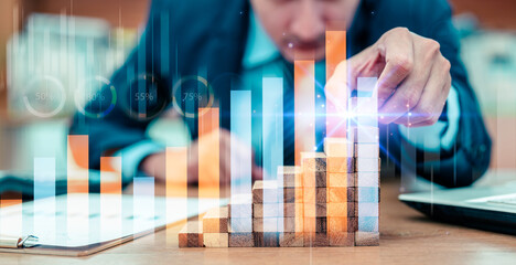 Businessman hand putting placing wood block on the tower and semi-pyramid in modern office. Plan business development ideas, investment graph and strategy in business concepts.