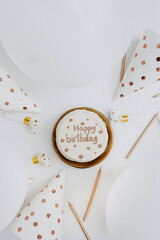 Birthday cake, candles, balloons, party hats on white background. Flat lay, top view. White and gold colours