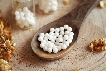 Obraz na płótnie Canvas Homeopathic pills on a spoon on a table