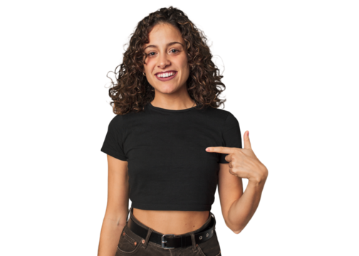 Radiant young woman with stunning curls person pointing by hand to a shirt copy space, proud and confident