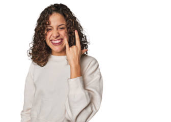 Radiant young woman with stunning curls showing rock gesture with fingers