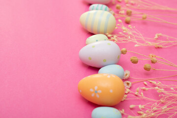 Fototapeta na wymiar Happy Easter holidays. Banner or greeting card background with Easter eggs and dry flowers. Composition with Easter eggs and pink background. Flat lay, top view, copy space.