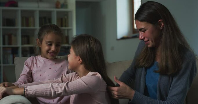 Portrait of Woman and her Daughters: Mother Brushing her Child's Long Hair While Talking to her, Sister Watching Them. Authentic, Affectionate and Bonding Moment Between Mother and her Kids