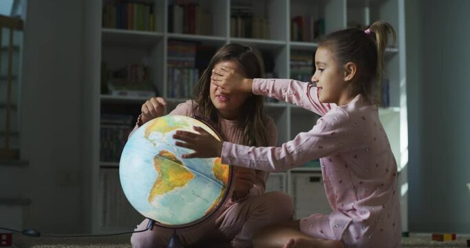 Portrait of Two Happy Curious Little Girls Using a Globe at Home Together to Learn More about Geography and Countries. Sisters Playing Using a Map, Choosing Random Travel Destinations For the Family.
