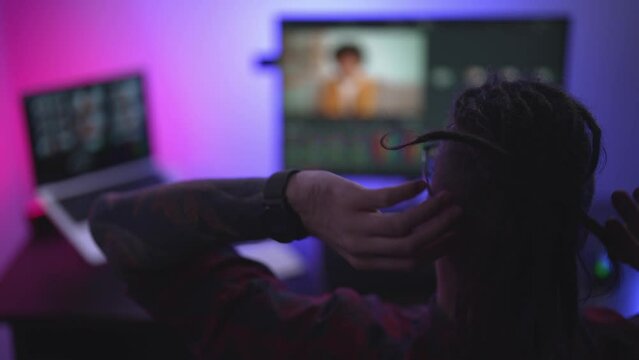 Young man in glasses working on video editing on computer doing montage and color correction. Professional man hand making edits on a special panel. Concept of creating video content.