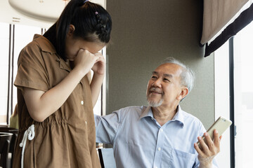 Sad teenager niece crying with her grandfather who having smartphone problem, concept of technology...