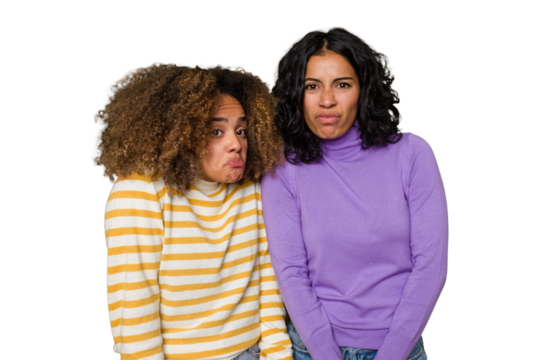 Two female friends isolated in studio shrugs shoulders and open eyes confused.