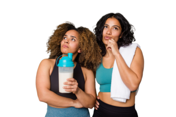 Two best friends are ready to go to the gym, one of them holds a protein shake, looking sideways with doubtful and skeptical expression.