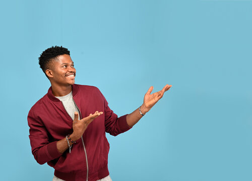 Handsome young Africa man pointing up to copy space and looking off camera with smile face and happy Pretty guy act like a satisfied product, use for advertising with isolated on blue background