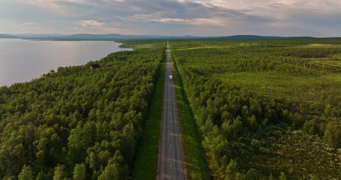 Aerial view following a caravan driving in arctic tundra nature on a summer evening
