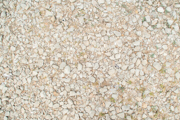 Background with gravel and grass growing between the stones. Small pieces of granite scattered on the ground.