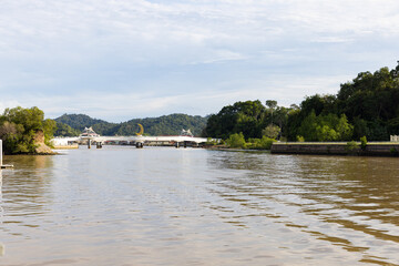 trees, boat and building along Sungai Kedayan river, the capital of Brunei Darussalam in sunny day with white coulds and blue sky
