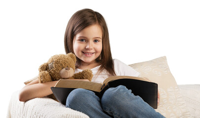 Cute child girl reading a book in bed before going to sleep