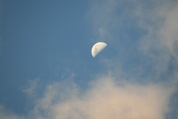 Half moon with blue sky and white clouds on background