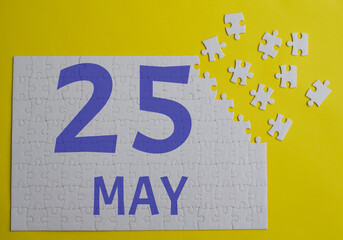 25 may calendar date on a white puzzle with separate details. Puzzle on a yellow background with a...