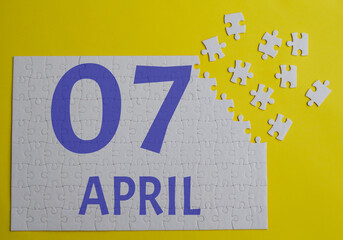 7 april calendar date on a white puzzle with separate details. Puzzle on a yellow background with a blue inscription