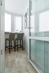 The modern fashion interior of the loggia. Black bar stools, bar, paintings on the wall, white blinds on the windows