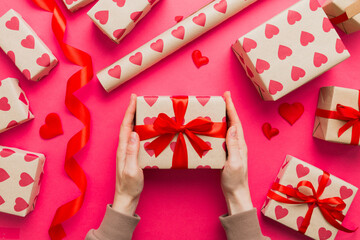 Give a gift on Valentine Day.Valentine gift. Beauty Woman hands holding Gift box with red bow over holiday background