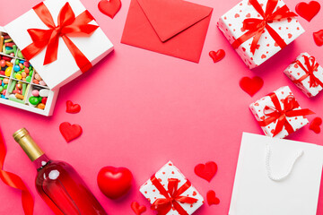 top view photo of st valentine day decor shopping, bag, wine, bottle, envelope, gift, box, candy and red heart on colored background with empty space. Frame background