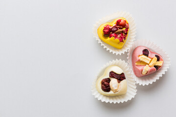 chocolate sweets in the form of a heart with fruits and nuts on a colored background. top view with space for text, holiday concept