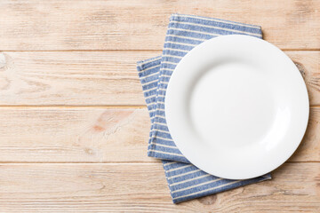 Top view on colored background empty round white plate on tablecloth for food. Empty dish on napkin with space for your design