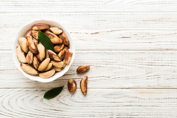 Fresh healthy Brazil nuts in bowl on colored table background. Top view Healthy eating bertholletia concept. Super foods