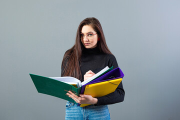 fashionable female holding a colorfuls folders with documents, isolated on dark background