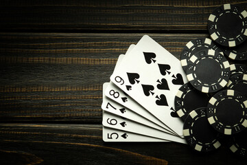 Playing cards with a winning combination of straight flush and chips on a black vintage table in a...