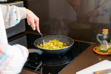 Girl cooking. Girl stirring vegetables in paella. Mushrooms, green and red peppers and onion	
