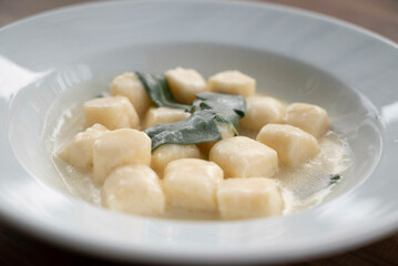 Gnocchi in sauce of sage butter, served in a deep plate, decorated with a sage leaf