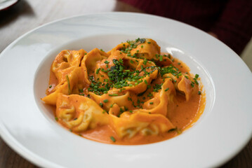 Ricotta and spinach ravioli in rose sauce, garnished with chives, served in a deep plate