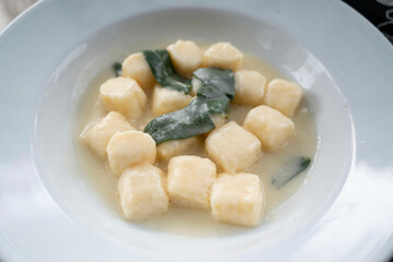 Gnocchi in sauce of sage butter, served in a deep plate, decorated with a sage leaf