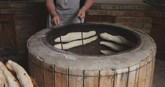 Woman Removing Georgian Shotis Puri Bread Sticking On The Stone Wall Of Tone Oven. - tracking
