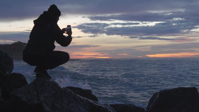 great sea waves at beach bay, man takes photos, enjoys dusky view at blue hour