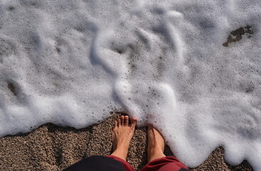 barefoot to the foaming wave of the sea. View from above