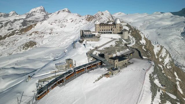 Beautiful Drone Shot Above Gornergrat Observation Platform as Train Arrives at Mountain Peak in Switzerland. Winter