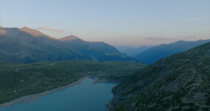 Aerial shot over a lake with mountains on the horizon at sunset in montespluga, Lombardy.