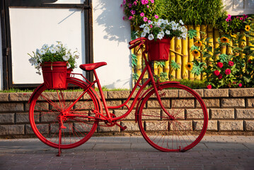 Fototapeta na wymiar Red bicycle with flowers in a garden