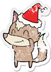 friendly distressed sticker cartoon of a wolf wearing santa hat