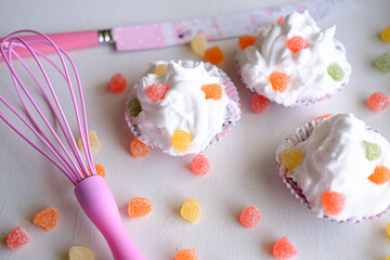 Three cupcakes with jelly beans on bright white background. Cupcakes with knife and orange, red, pink jellybeans for festive.
