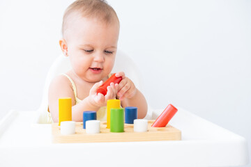 cute baby girl playing with colorful wooden blocks at child chair. early children development