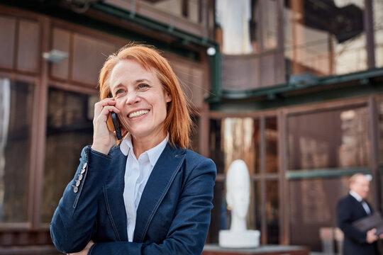 Ambitious middle-aged businesswoman, embracing unexpected challenges with a determined and professional attitude talking on mobile phone