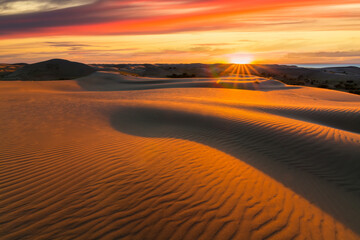 Fototapeta na wymiar Picturesque desert landscape with a golden sunset over the dunes