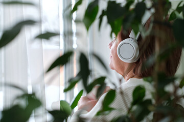 old lady with headphones, enjoying her coffee and music. technology can enhance the quality of life...