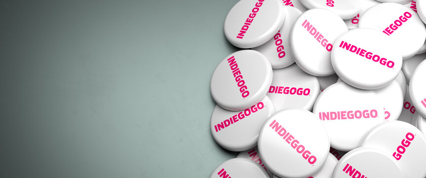 Logos of Indiegogo the crowdfunding platform and company on a heap on a table. Copy space. Web banner format.