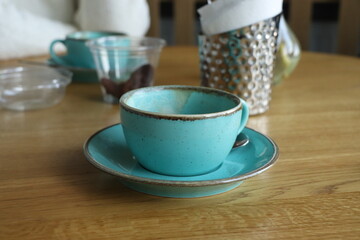 A cup of coffee. Empty coffee cup. Green cup. A cup on a wooden table.