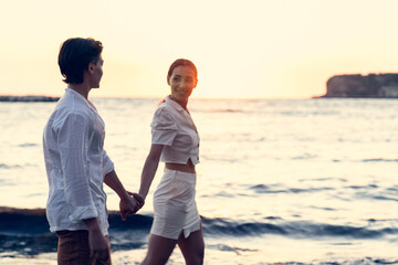 Photoshoot of young helthy beautiful caucasian couple, boy and girl, dating at the beach - Man and woman lovers having fun in holidays walking near the ocean in a sunny day