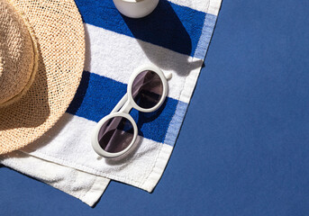 Summer vacation beach concept frame with retro sunglasses, striped towel and straw hat on the blue...