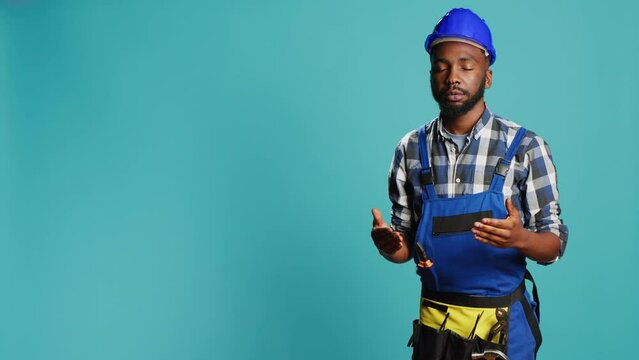 Professional builder almost fainting being wobbly, standing over blue background. Male construction worker feeling light headed with looney tunes cartoons stars on studio camera.