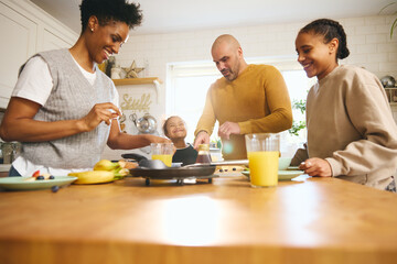 Family and boy with Down syndrome making pancakes for breakfast
